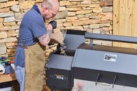 A person pours pellets into the Yoder Smokers YS640S Pellet Grill