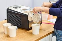 A person using a spatula to move ice cream from the Cuisinart Compressor Ice Cream and Gelato Maker into a pint
