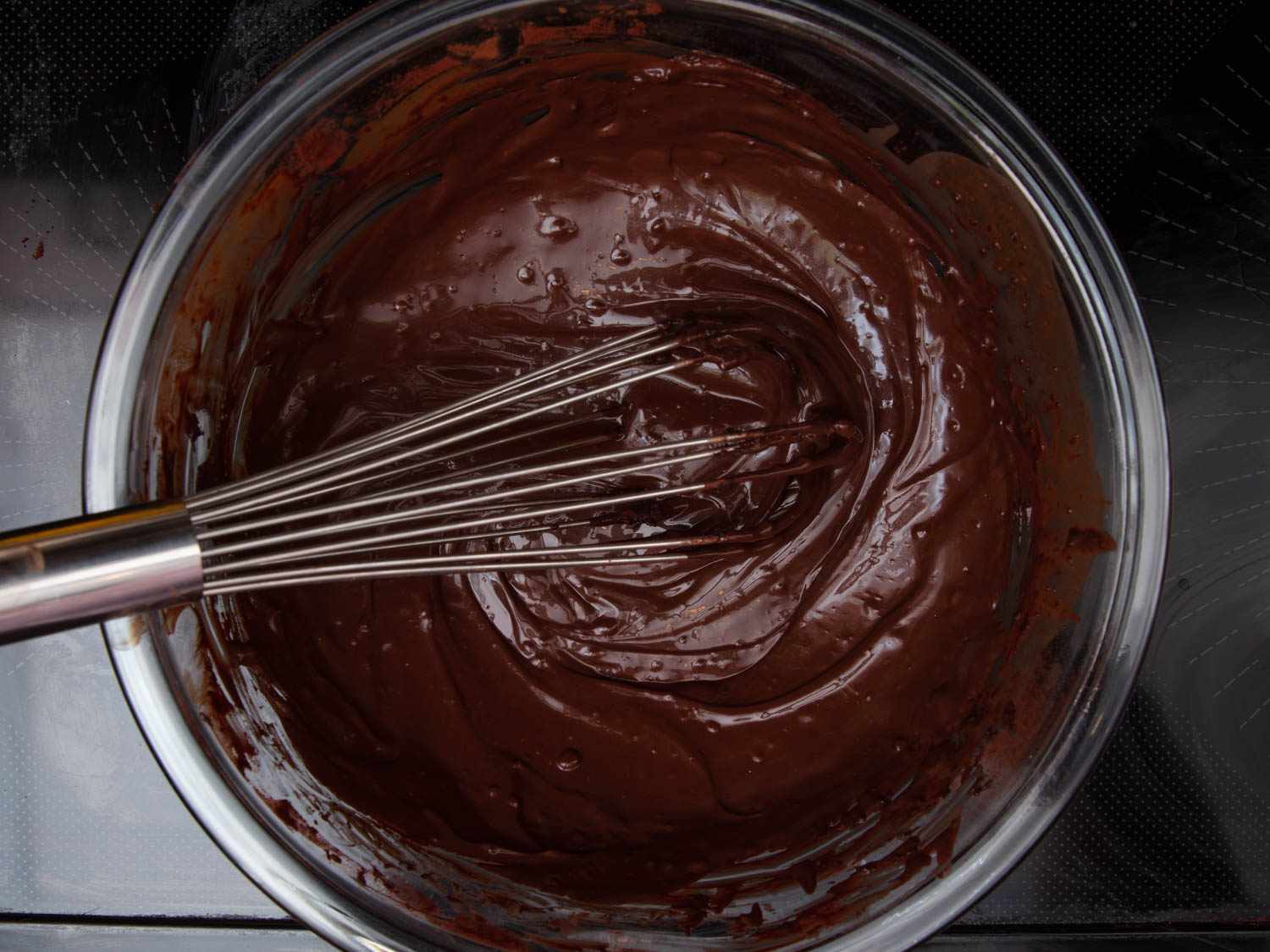Melted chocolate being whisked in a bowl.