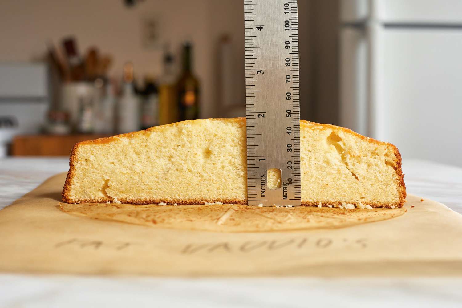 A person using a ruler to measure the rise of a cake