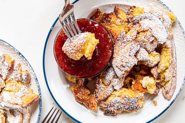 Kaiserschmarrn served with a side of red fruit jam on a plate with a fork lifting a piece of the dish