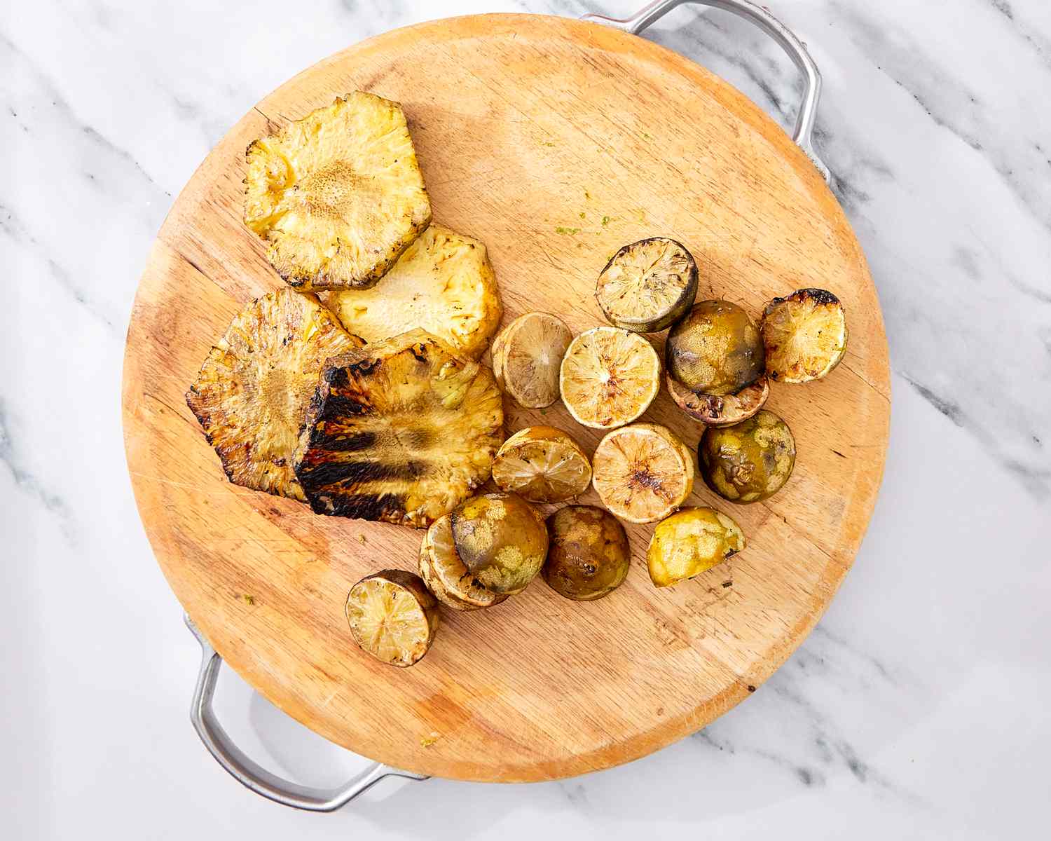 Cut grilled pineapple and lime slices on a wooden serving board