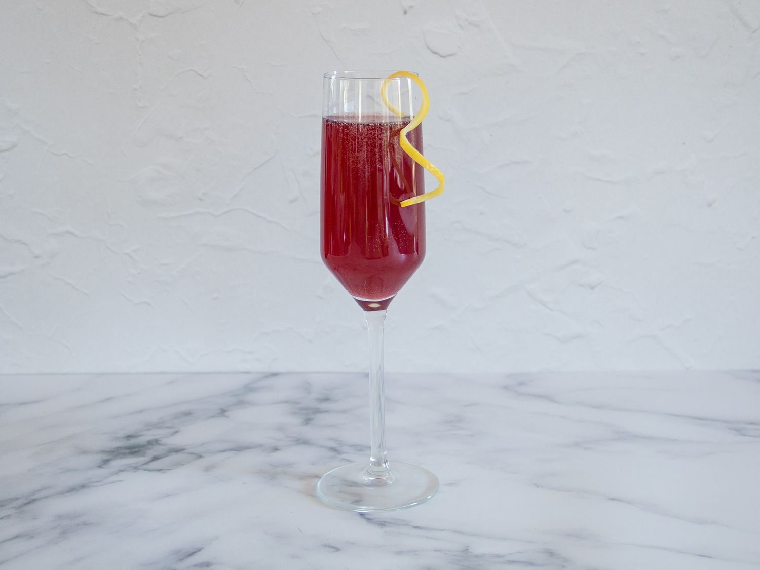 Pomegranate rouge cocktail garnished with a lemon twist.