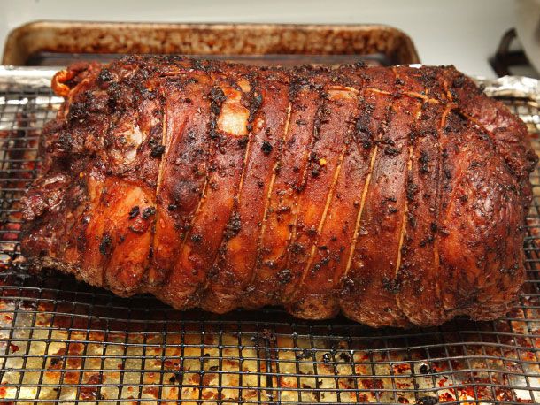 Cooked and crisped lamb roast resting on a wire rack on a rimmed baking sheet.