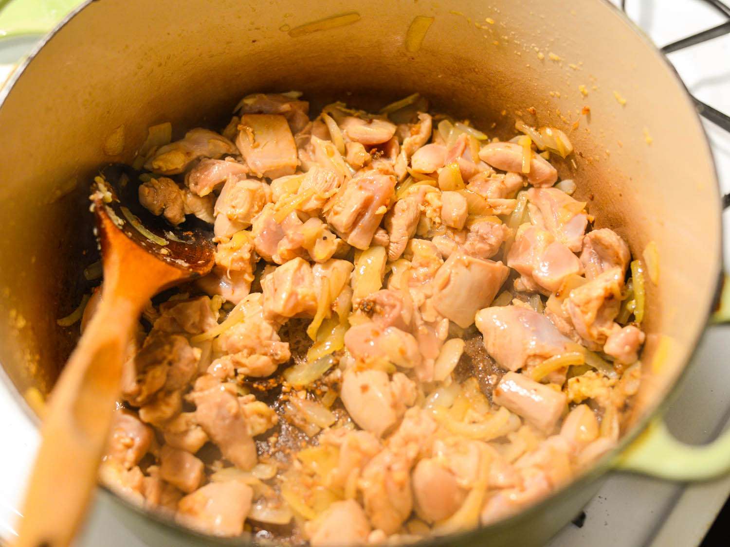 Bite-sized pieces of chicken have been stirred into the Dutch oven.