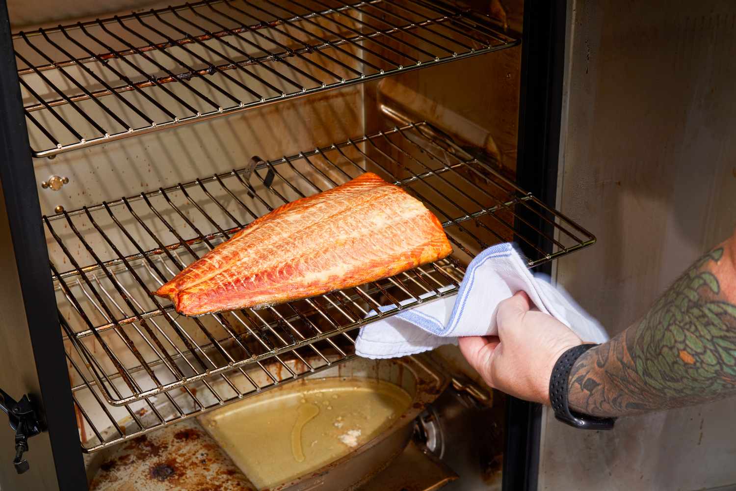 A person removes salmon from the Masterbuilt 40-Inch Digital Electric Smoker (MB20072918)