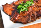 Sliced beef brisket with apricot-cranberry sauce, garnished with parsley leaves on white platter