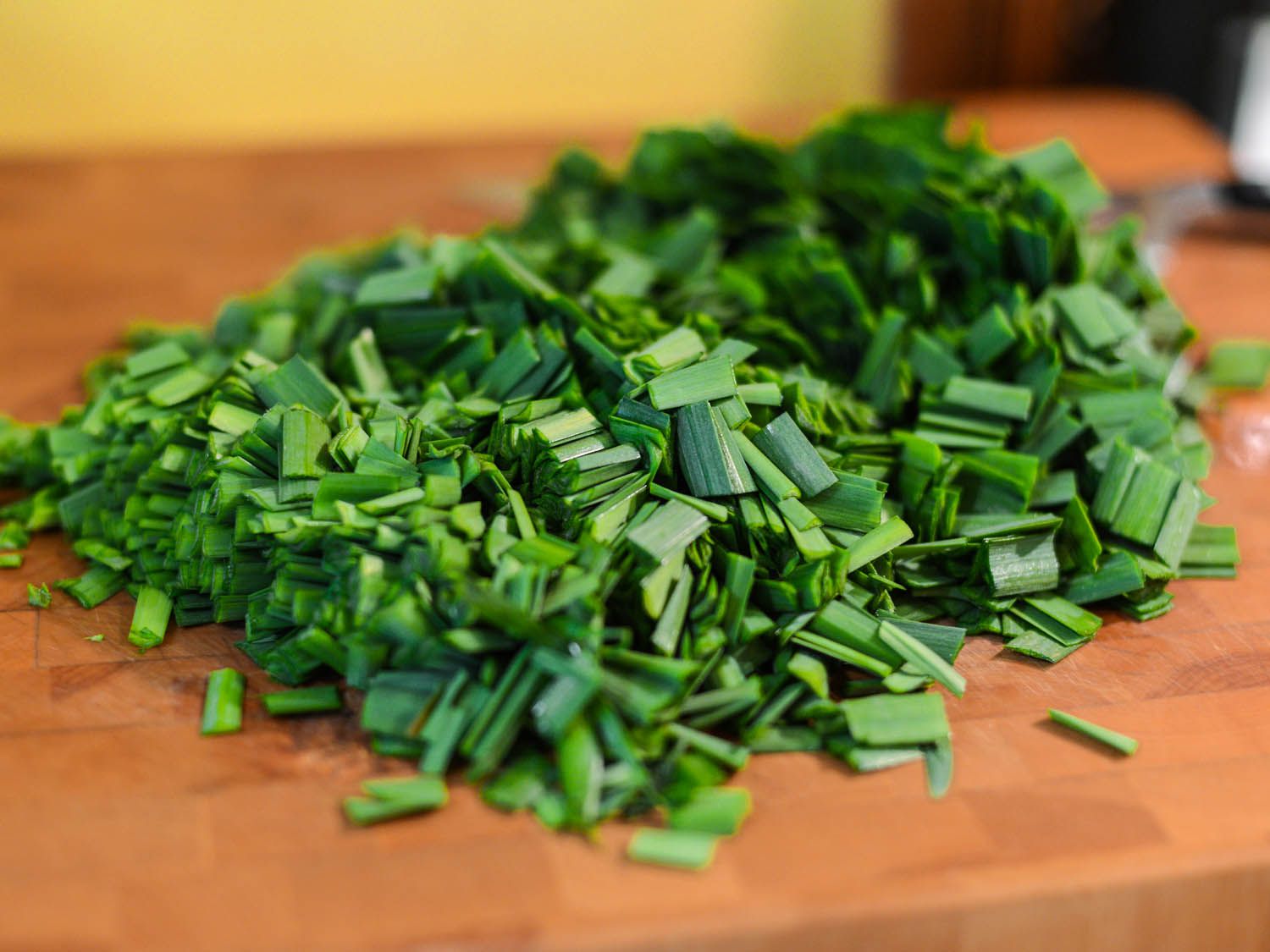 Chopped Chinese chives on a wooden cutting board.