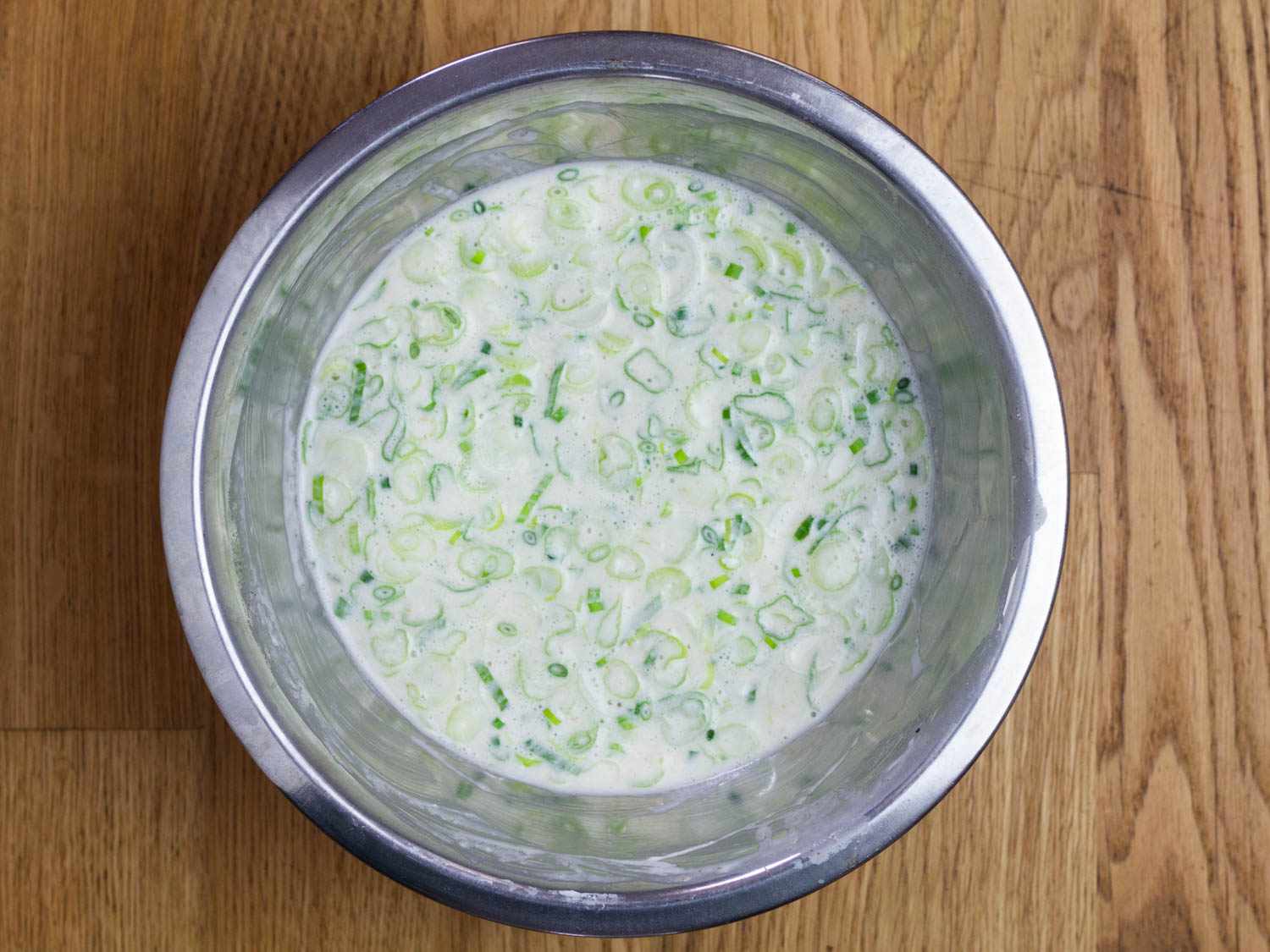Overhead of metal bowl filled with batter for scallion sourdough pancakes.