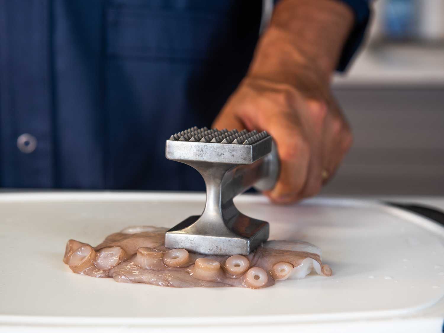 Pounding a piece of octopus with a meat tenderizer