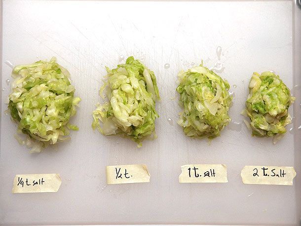 Four labeled piles of shredded cabbage prepared with different amounts of salt and drained