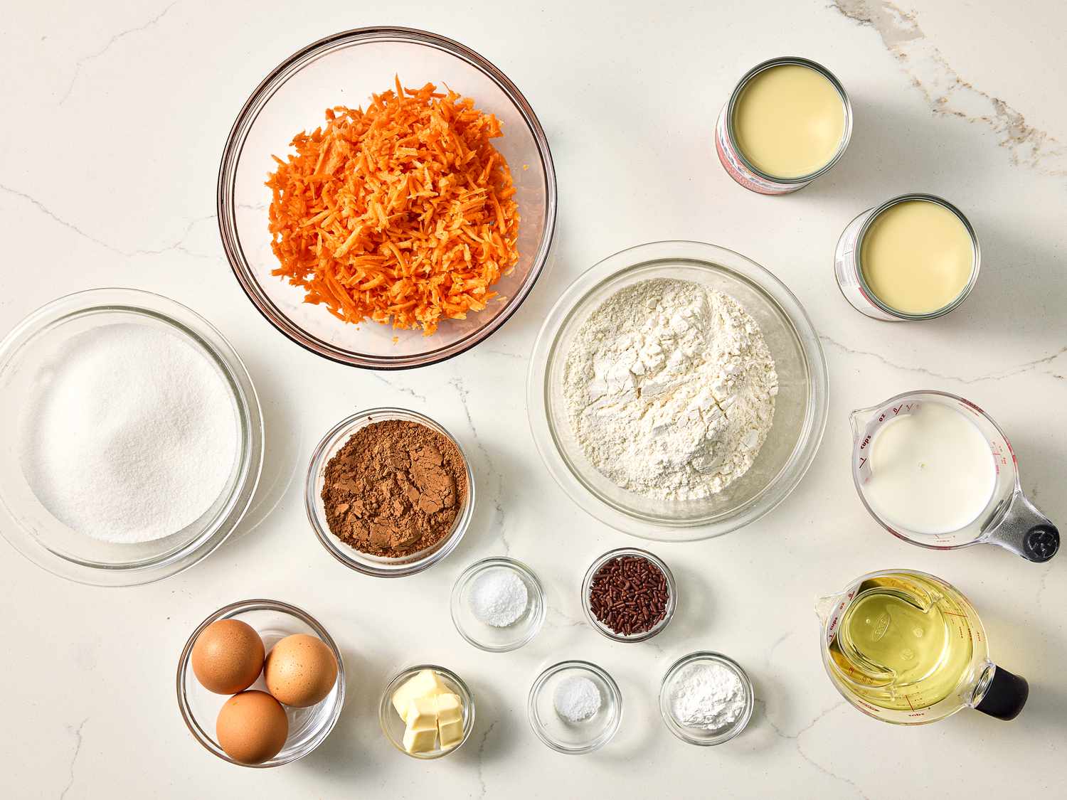 Ingredients arranged for Brazilian carrot cake, including grated carrots, flour, sugar, eggs, and oil on a counter