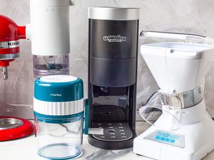 Kitchen countertop with various ice shaving appliances and a red KitchenAid mixer