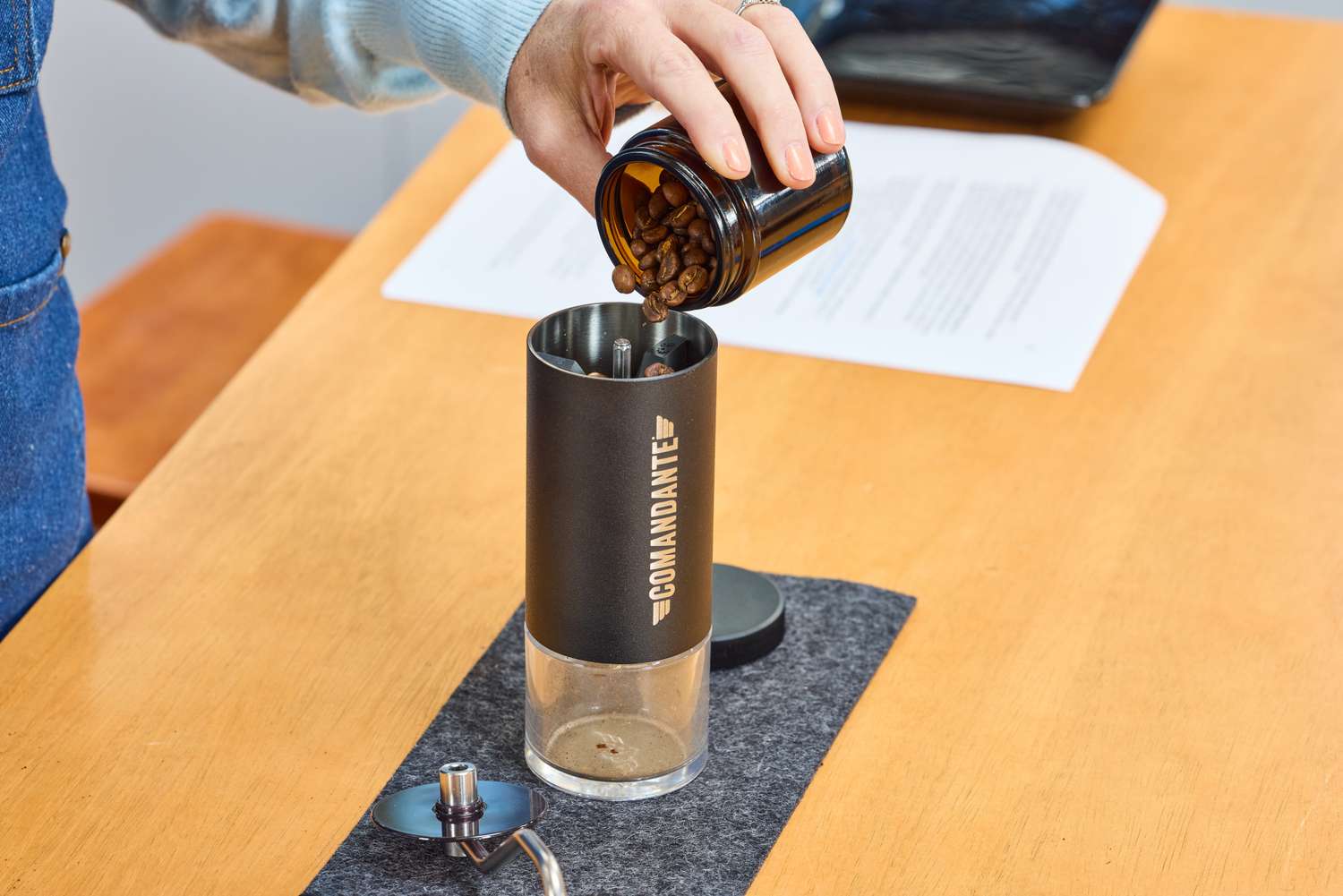 A person pours coffee beans into the Comandante C40 Nitro Blade Grinder