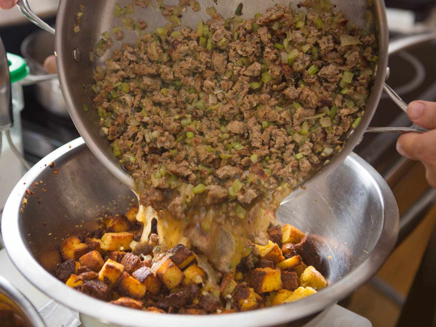Folding sausage and aromatic mixture into cornbread cubes for cornbread dressing. 