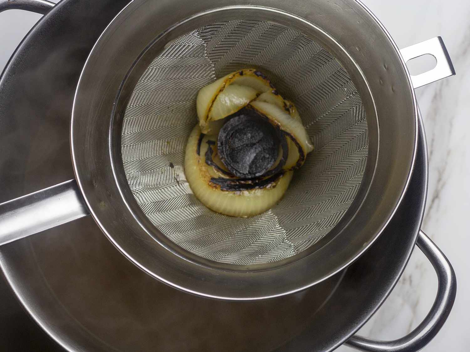 Charred onion slices atop a strainer.