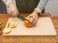 a person cutting the peel off of an orange on the yoshihiro cutting board