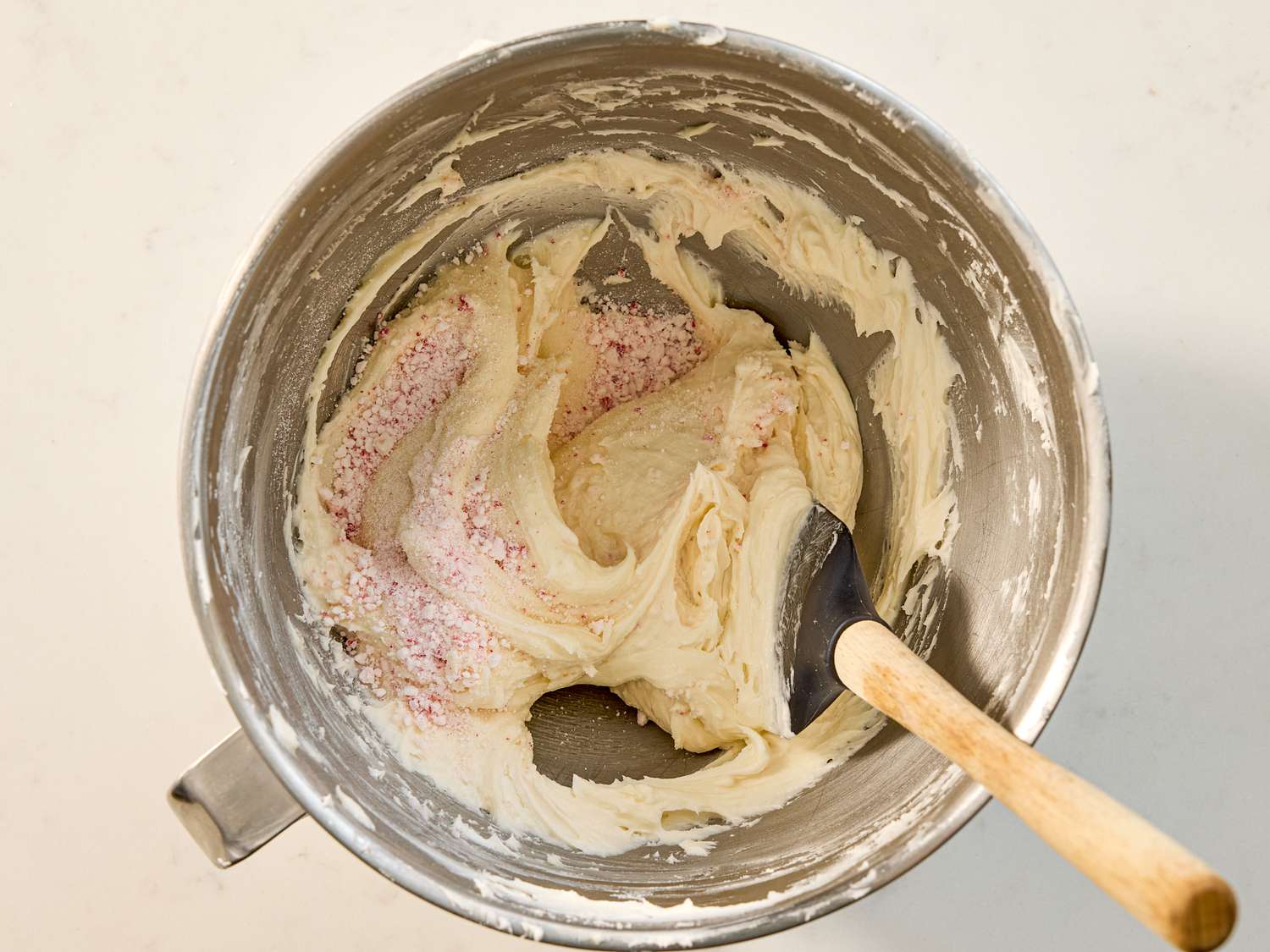 Cookie dough mixture with pink sugar in a mixing bowl with a spatula
