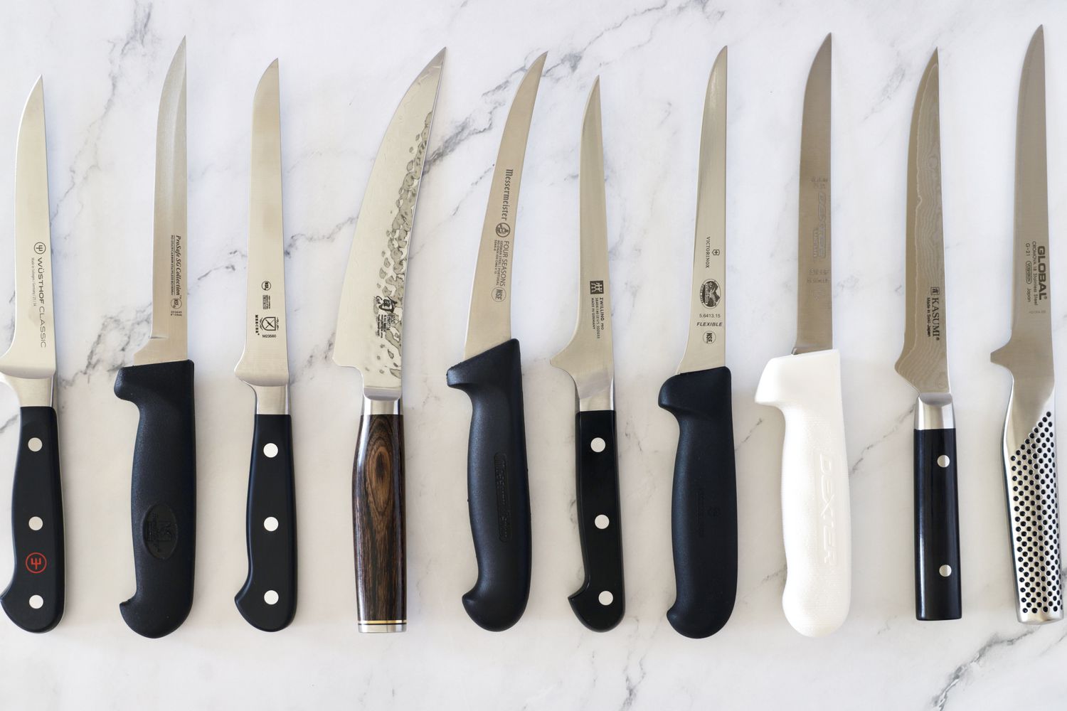 A selection of boning knives on a marble countertop
