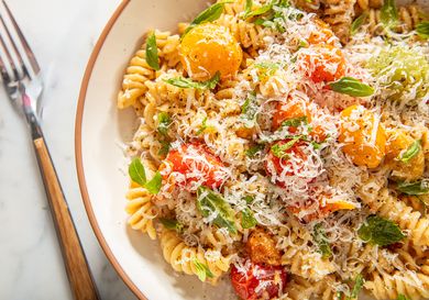 Bowl of pasta with roasted vegetables and grated cheese
