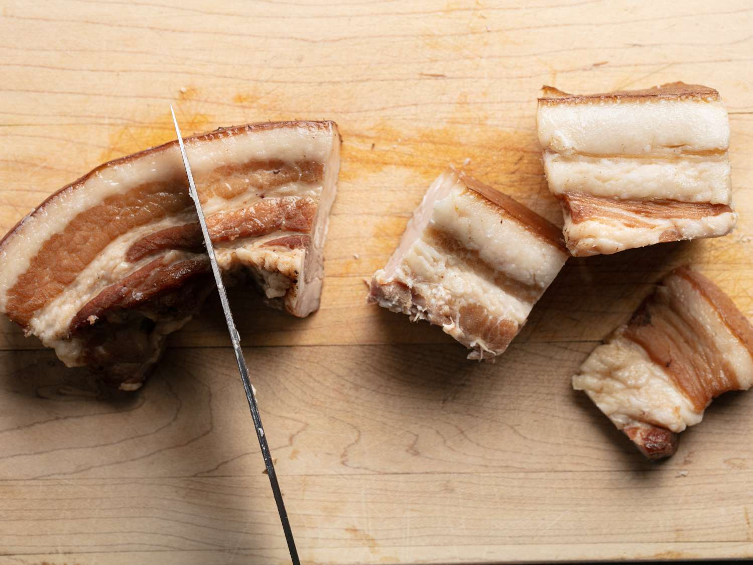 The cooked pork belly after it has been refrigerated overnight, being cut into 2-inch pieces.