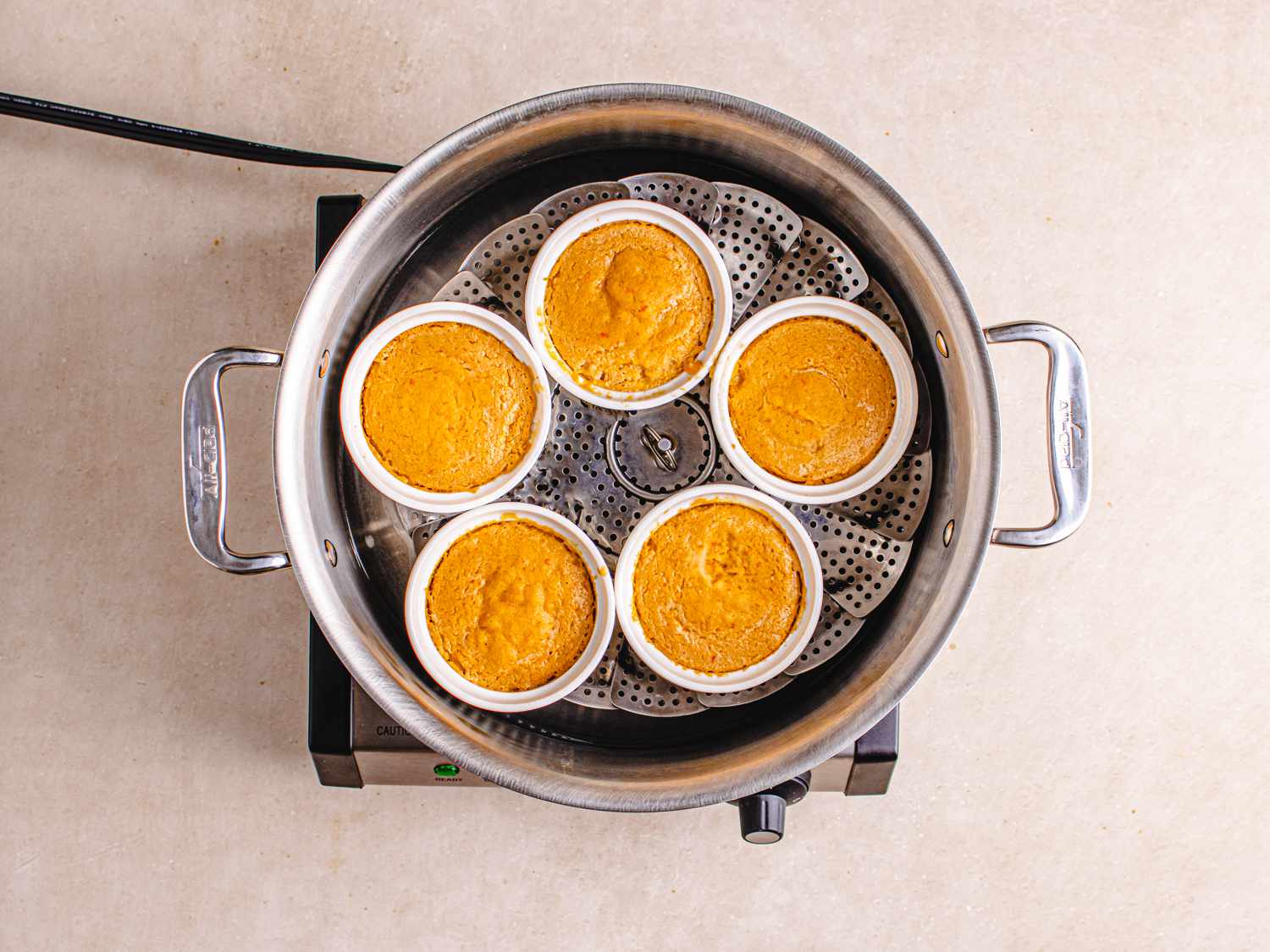 Overhead view of cooked moin moin in ramekins in steamer pot