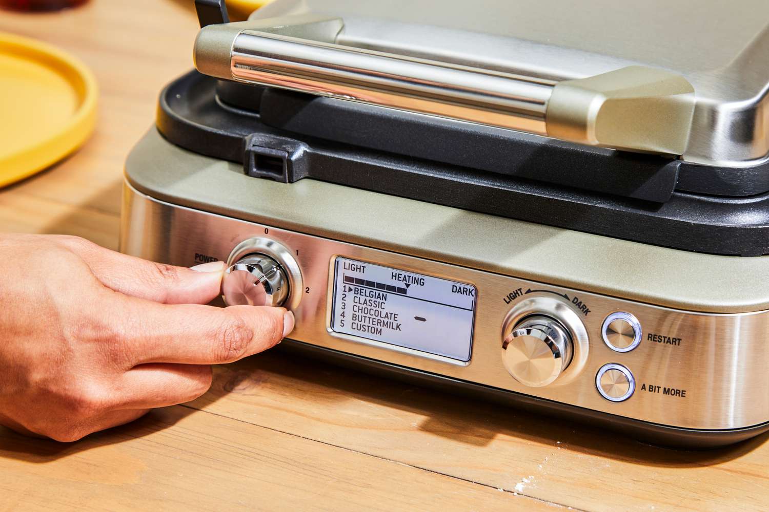Person turning knob on Breville The Smart Waffle Pro 4-Slice Waffle Maker