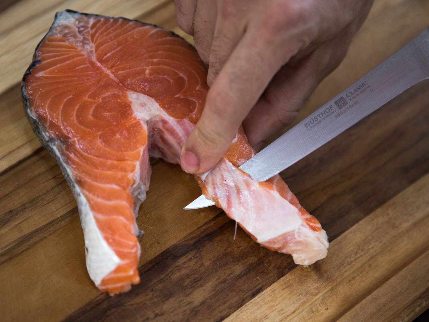 Cutting between the meat and the belly flaps with a knife.