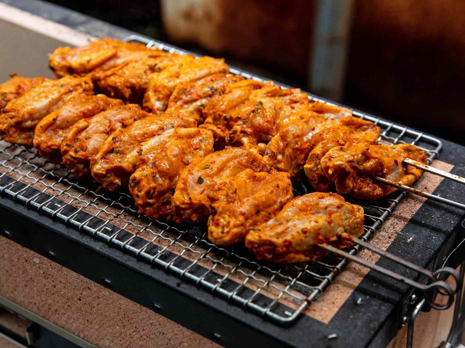Turkish-style wings that have just begun to cook on top of a mesh wire rack on a Japanese konro charcoal grill.