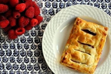 Overhead view of a raspberry jalousie, served on a small plate next to a clamshell container of raspberries.