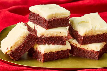 red velvet brownie squares stacked together on a gold platter on top of a red velvet backdrop