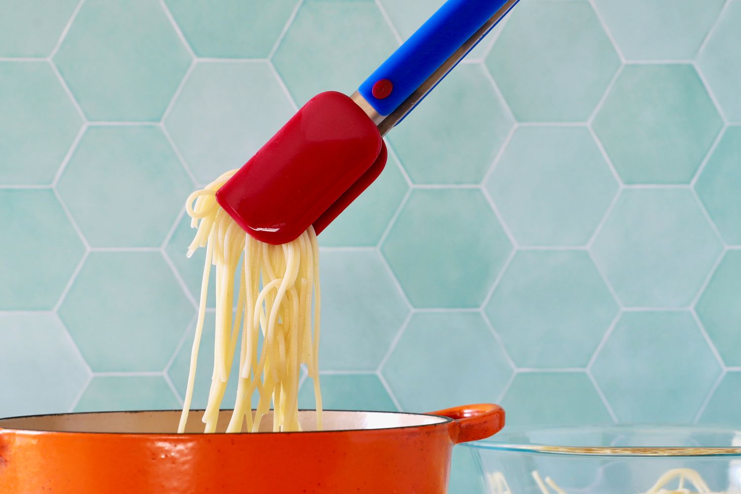A person using the Great Jones Great Tongs to pick up pasta