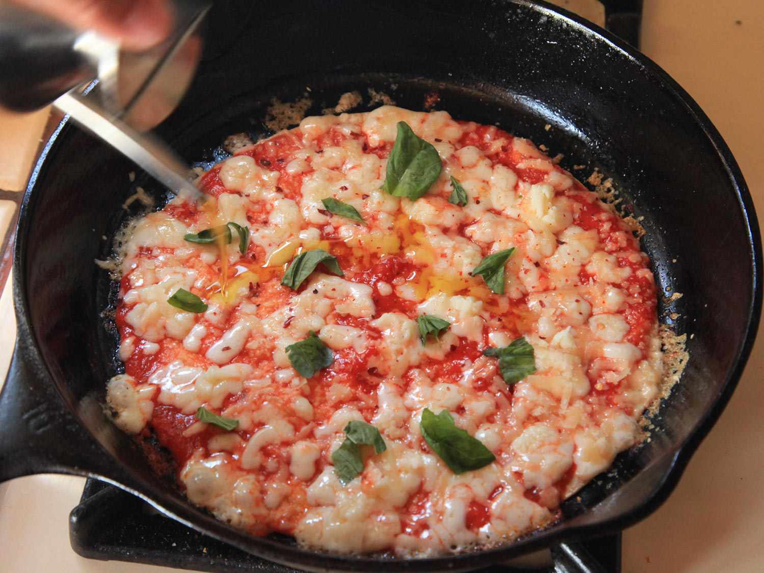 The pizza is topped with basil and drizzled with olive oil.