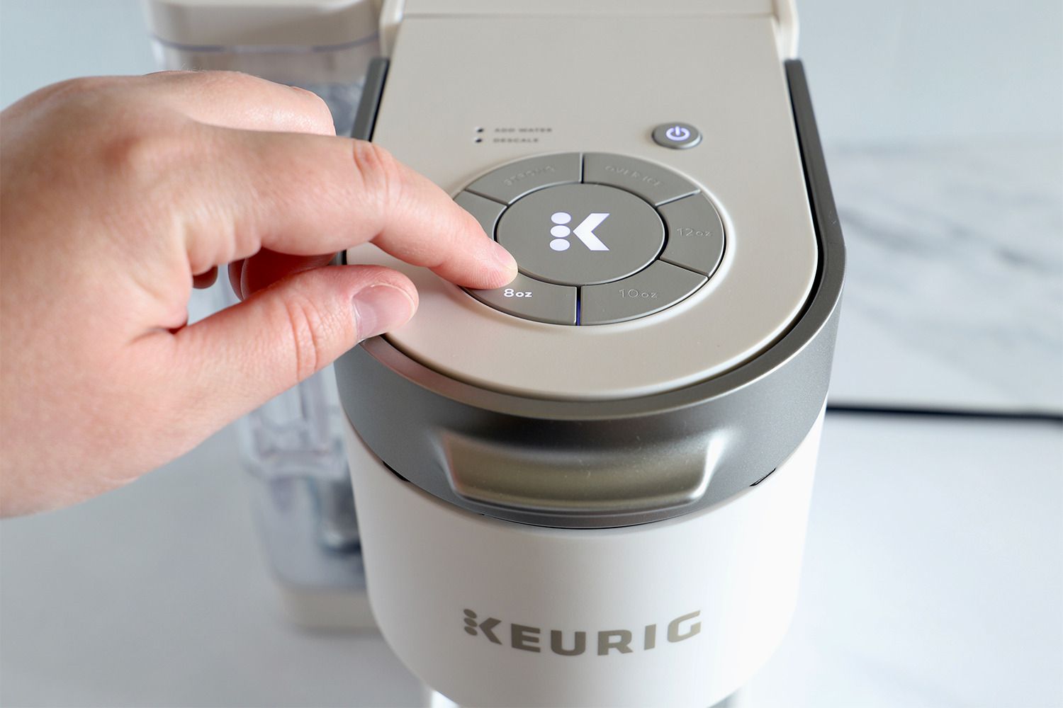 Person operating the Keurig K-Supreme Single Serve K-Cup Pod Coffee Maker