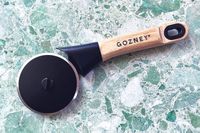 Pizza cutter with Gozney logo on a marble surface