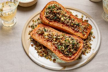 Butternut squash halves stuffed with a spiced couscous and mixed topping served on a white plate