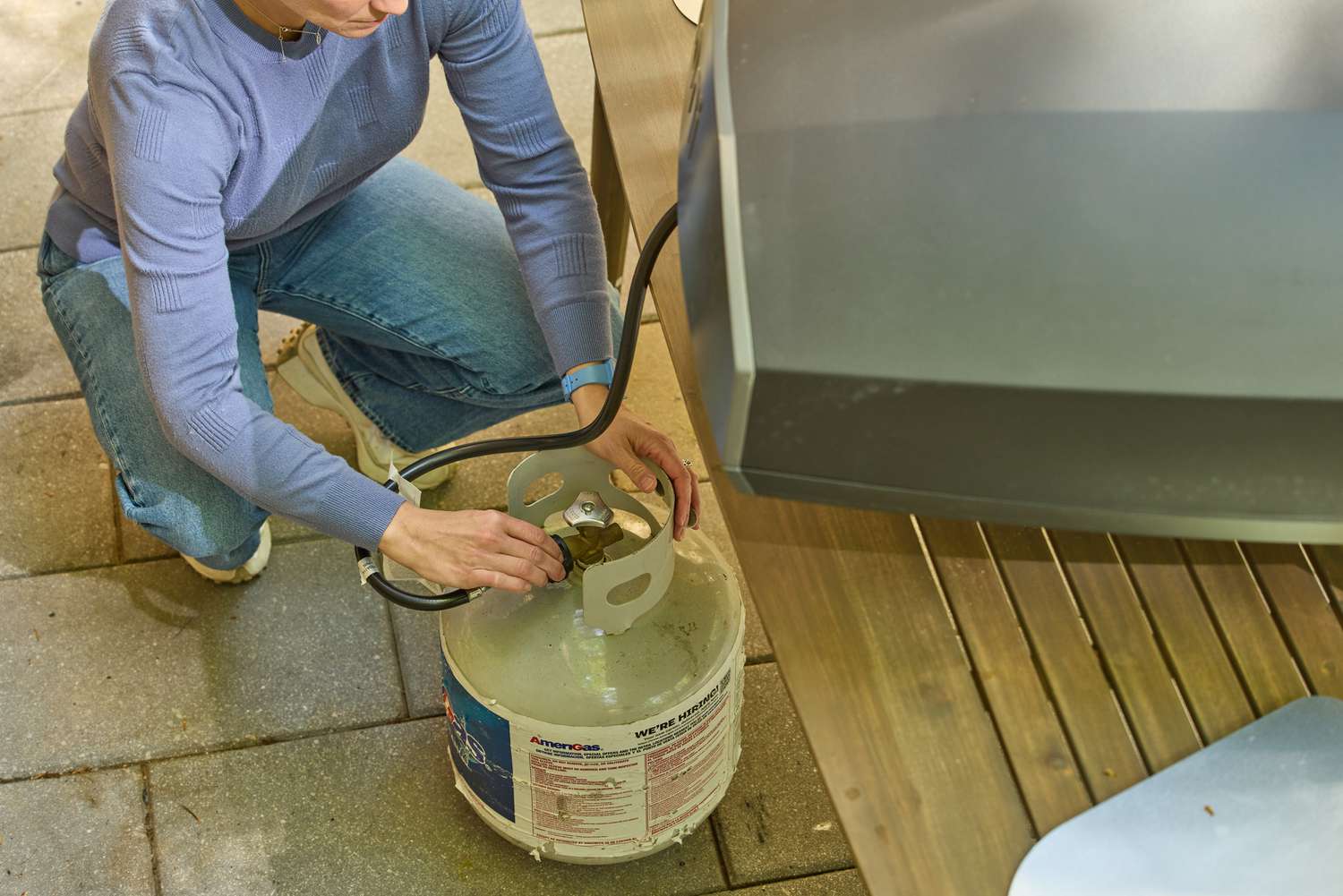 A person attaches the Ooni Koda 2 Max Gas Powered Pizza Oven hose to a propane tank