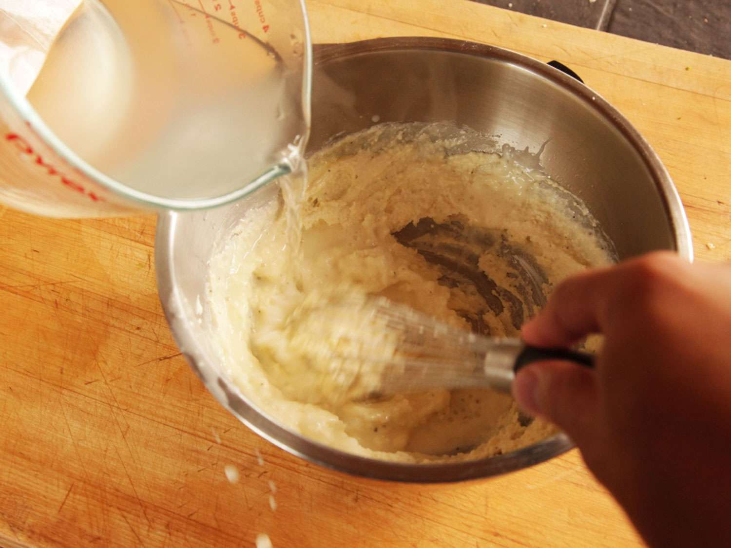 Whisking warm pasta water into cheese mixture.