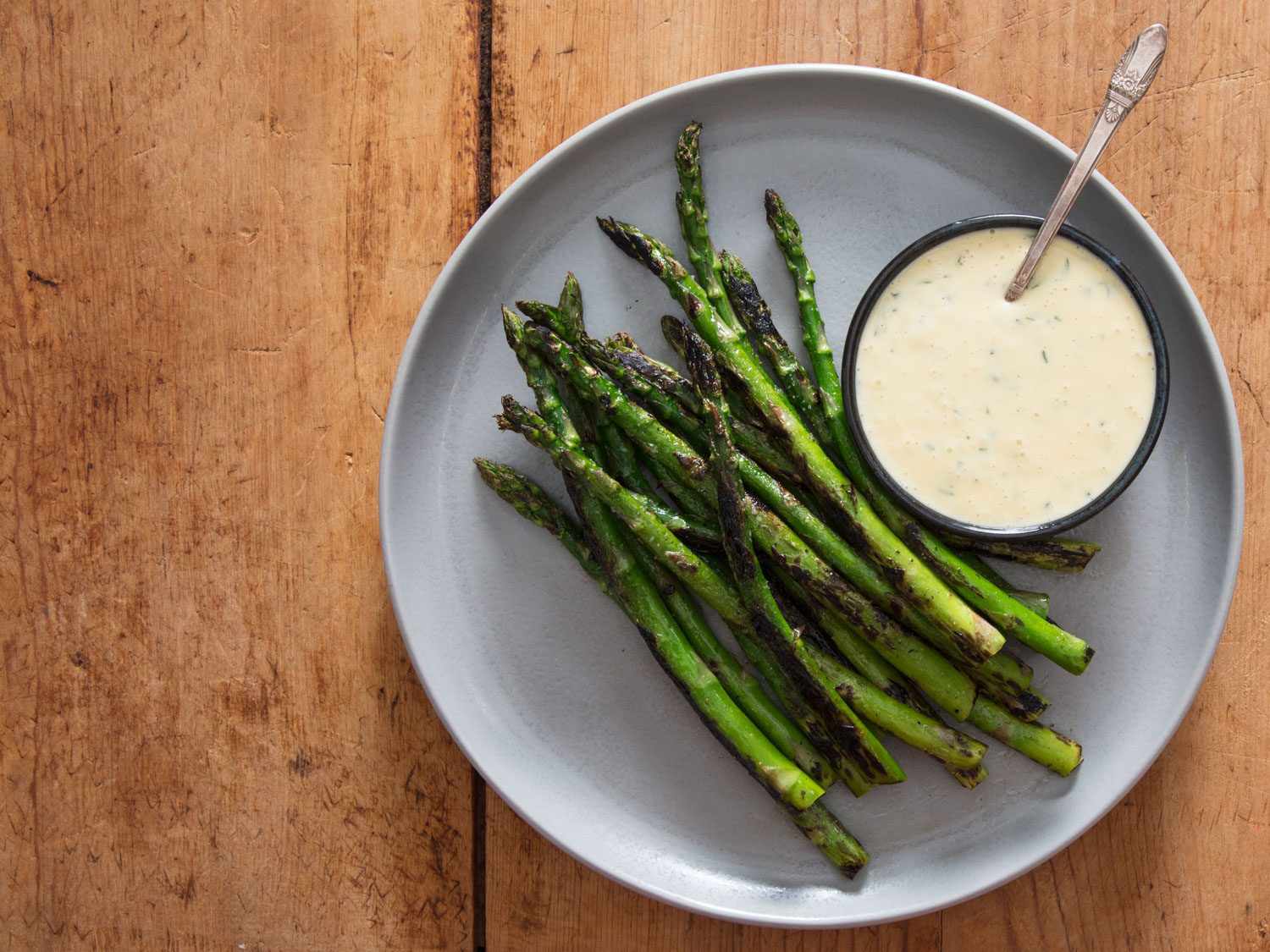 Overhead shot of charred asparagus with a bowl of miso béarnaise.