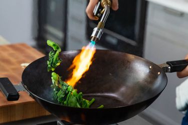 Blowtorching vegetables in a wok