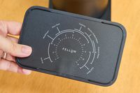 A person holds up a piece of the Fellow Ode Gen 2 Coffee Grinder