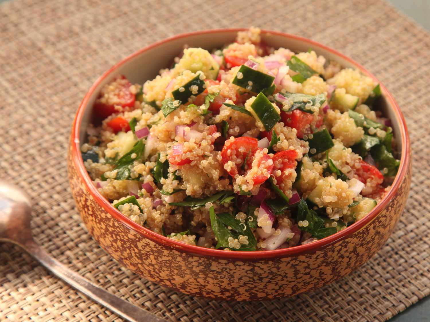 A small bowl filled with make-ahead quinoa salad with cucumber, tomatoes, and herbs.
