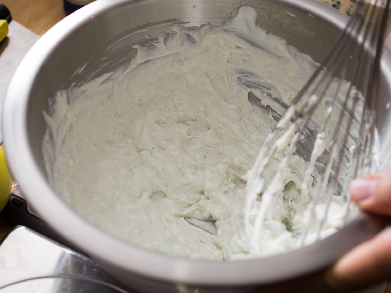 A fully whisked blue cheese dressing resting in a metal bowl.
