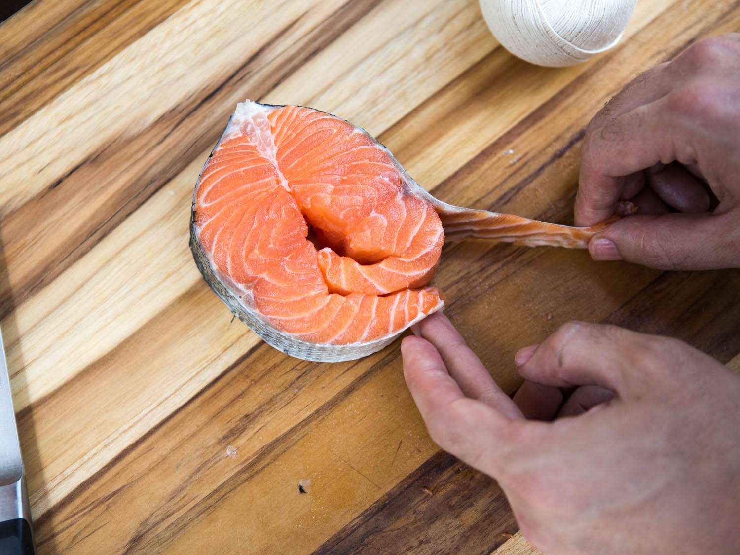 Tucking in the second belly flap to form a tight roll with a salmon steak.