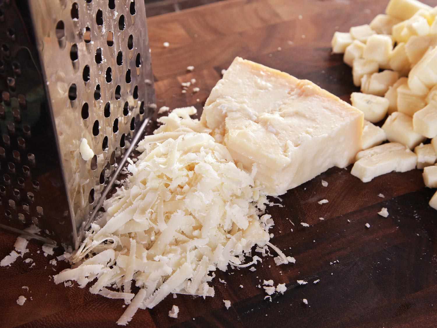 Close-up of a mound of grated Parmesan next to a box grater.