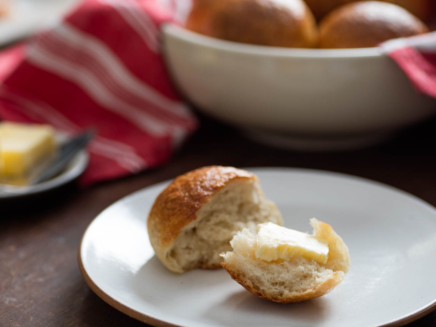 A split dinner roll with a pat of butter. 