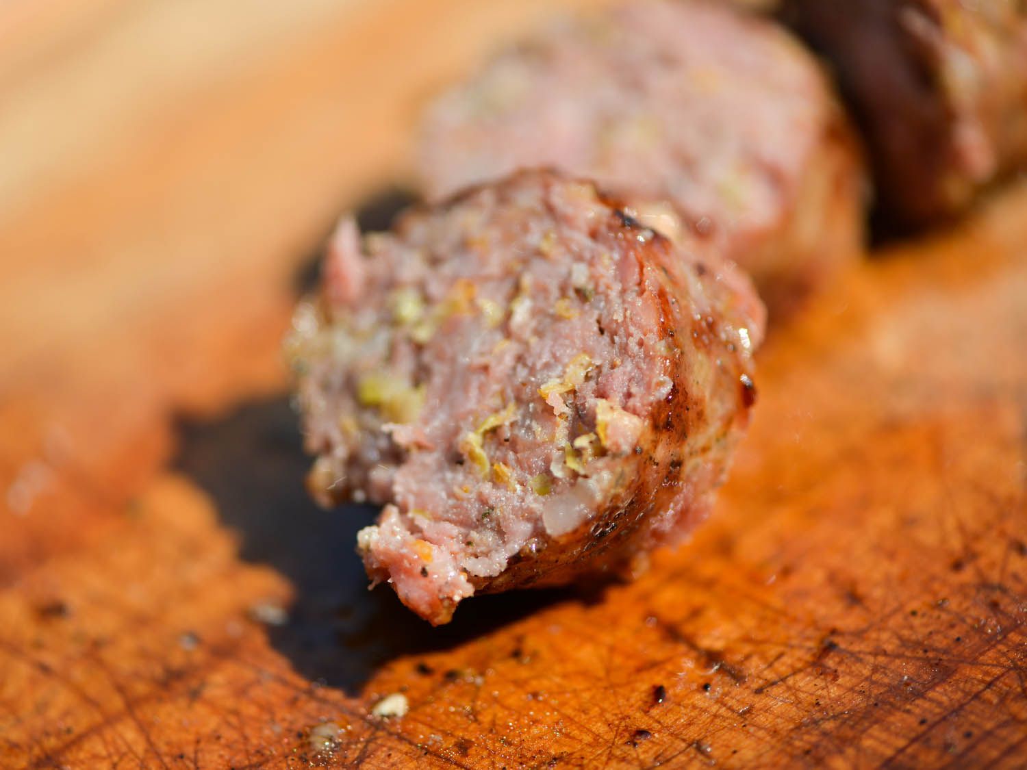 Close-up of a sliced loukaniko sausage. The interior is flecked with bits of leek.
