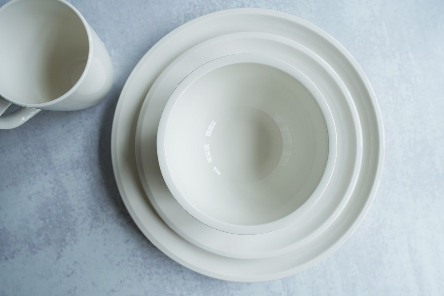 A white dinnerware place setting on a grey surface