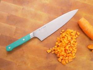 the misen chef knife on a wooden cutting board with a diced carrot