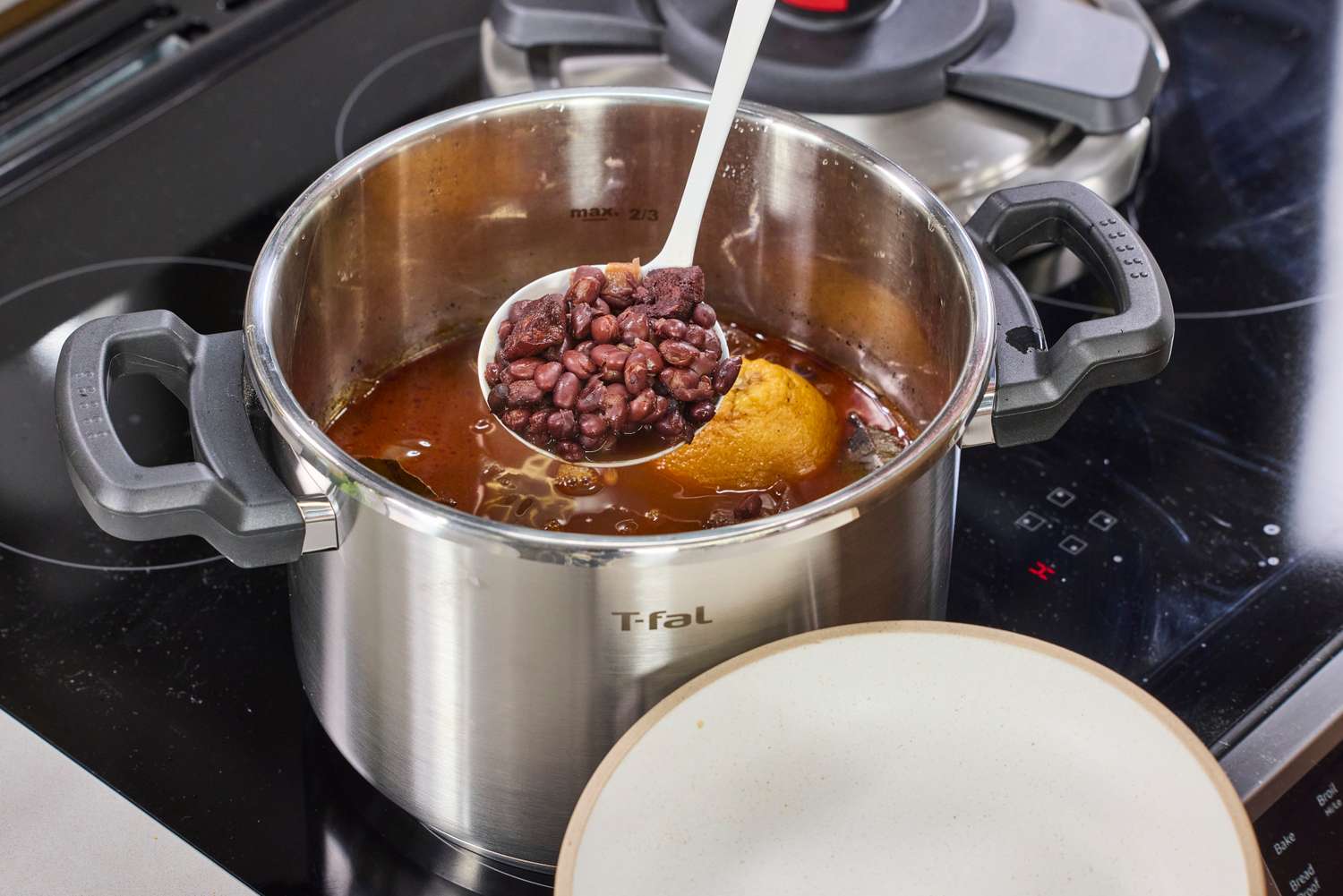 A person ladles beans from the T-Fal Clipso Pressure Cooker